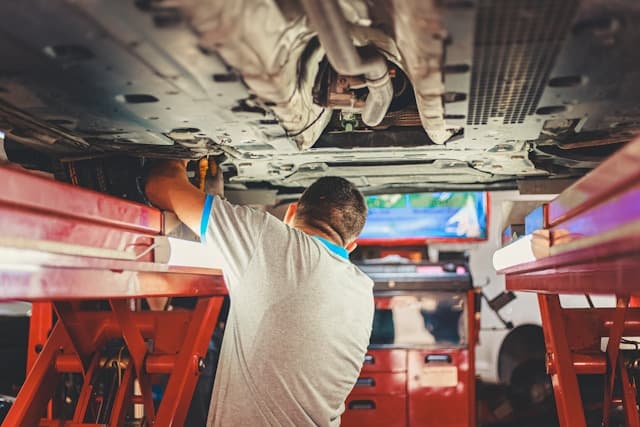 Technician inspecting vehicle under lift